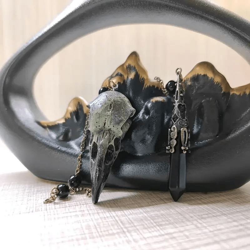 Figura de calavera de cuervo vikingo de Olivenorma con péndulo de obsidiana natural