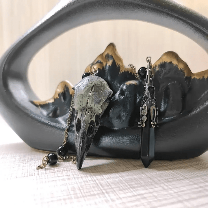 Figura de calavera de cuervo vikingo de Olivenorma con péndulo de obsidiana natural