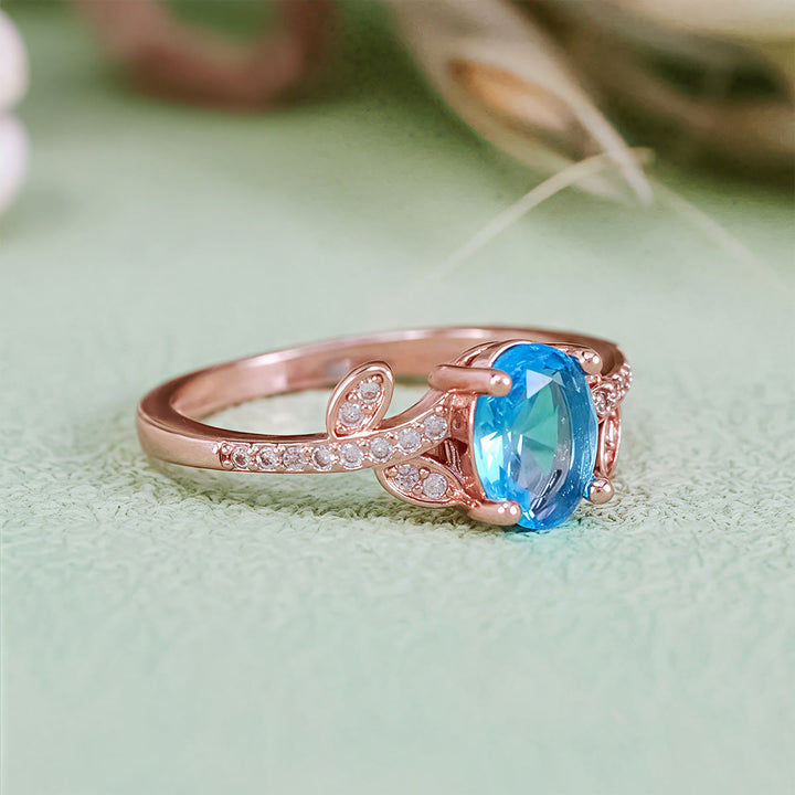 Anillo de hojas envueltas con topacio azul de talla ovalada de Olivenorma
