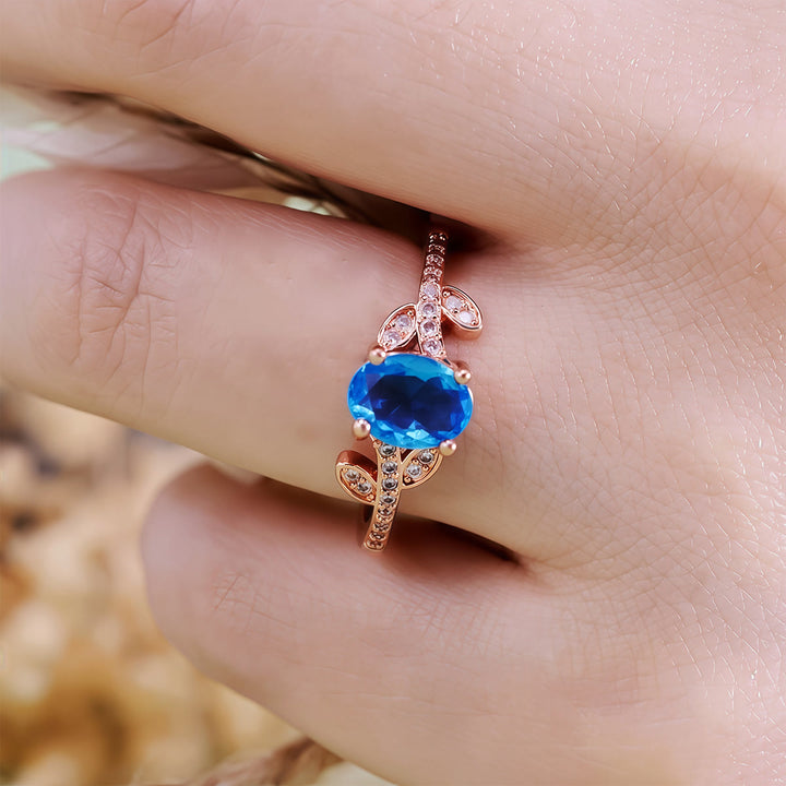 Anillo de hojas envueltas con topacio azul de talla ovalada de Olivenorma